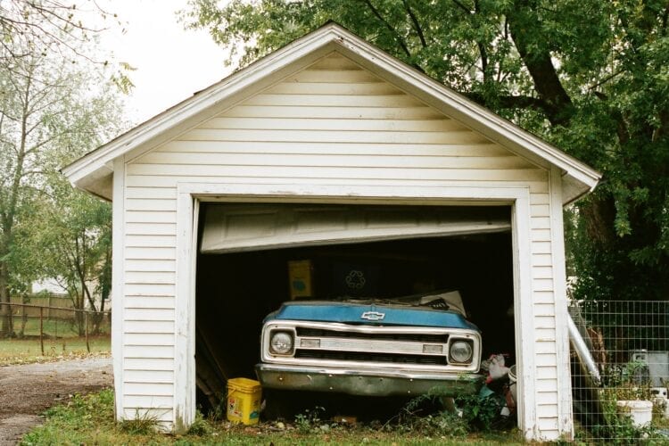 blue chevrolet car parked beside white wooden house